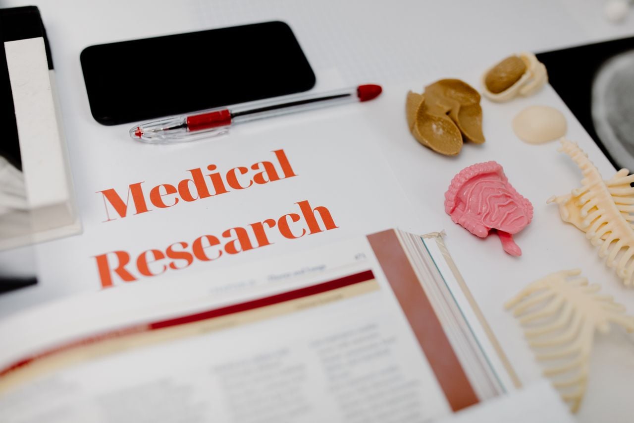 A pen, a mobile phone, and anatomical figures next to published medical research